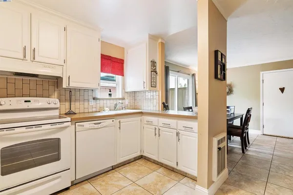 a kitchen with a stove a sink and white cabinets
