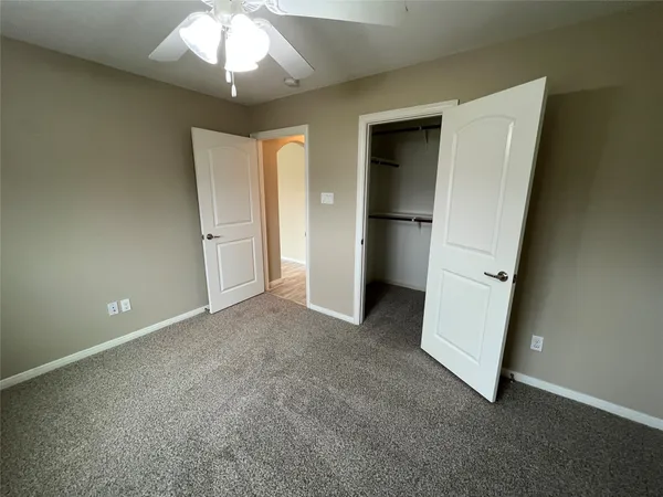 an empty room with chandelier fan and closet