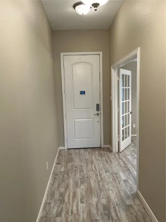 a view of a hallway with wooden floor and a bathroom