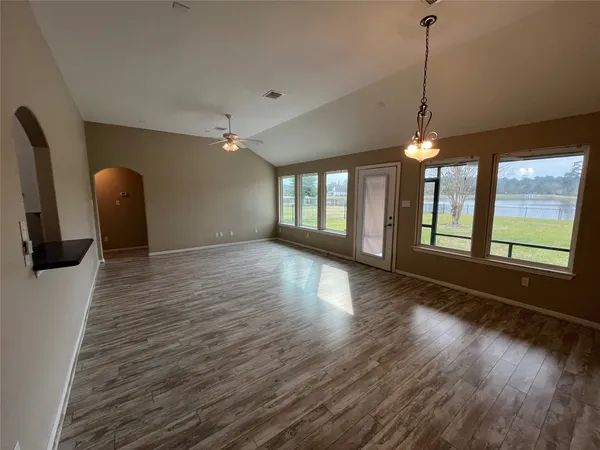 a view of an empty room with window and wooden floor