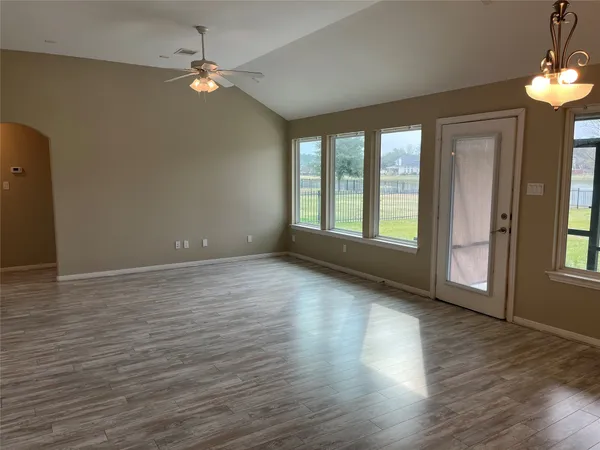 a view of an empty room with window and wooden floor