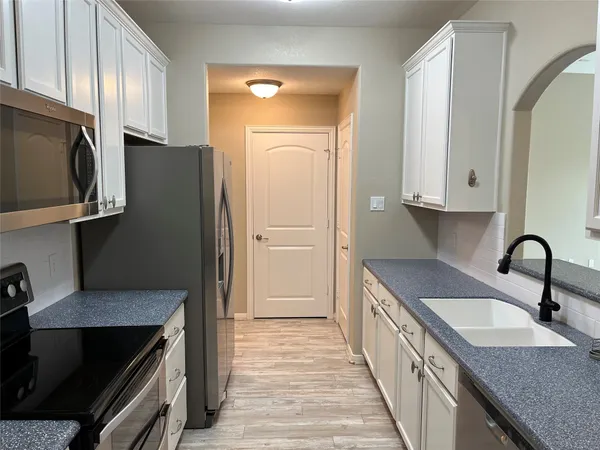a kitchen with granite countertop a stove top oven microwave and refrigerator