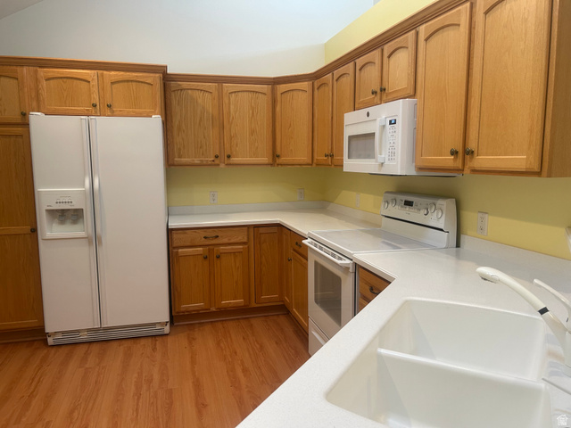 2043 Abbey View Road West Jordan, UT 84088 - Photo 5 of 15 Kitchen featuring wood-finish cabinetry, white appliances, solid surface countertops, and wood-finish flooring