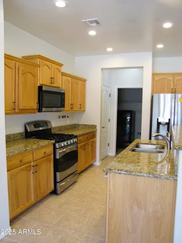 a kitchen with stainless steel appliances granite countertop a stove a sink and a refrigerator