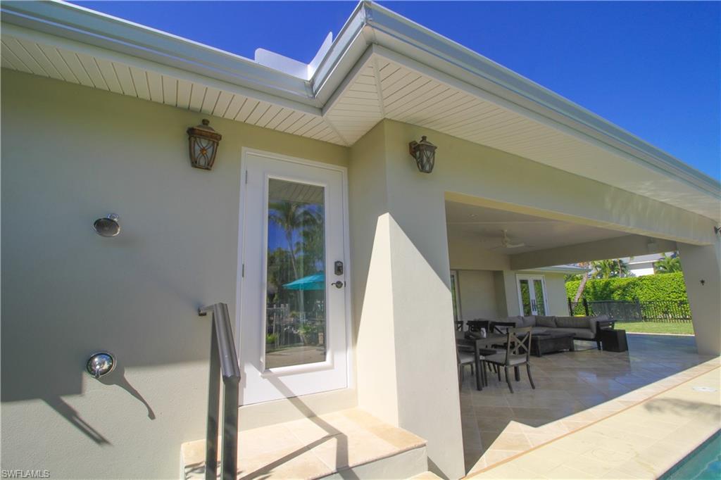 1645 Mullet Court Naples, FL 34102 - Photo 11 of 38 a view of a patio with table and chairs potted plants with wooden floor and plants