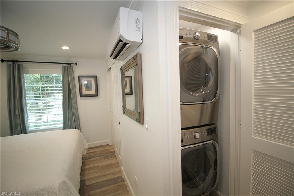 1645 Mullet Court Naples, FL 34102 - Photo 16 of 38 Laundry area with ornamental molding, stacked washer / dryer, an AC wall unit, dark wood-style floors, and recessed lighting