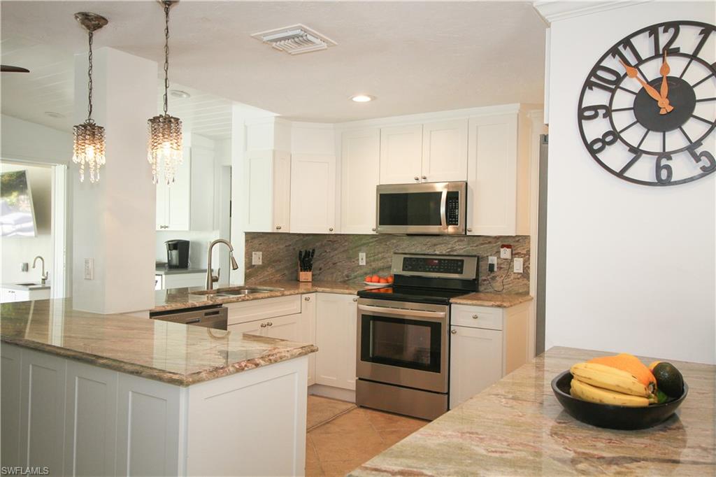 1645 Mullet Court Naples, FL 34102 - Photo 24 of 38 a kitchen with a sink and a stove top oven with wooden floor