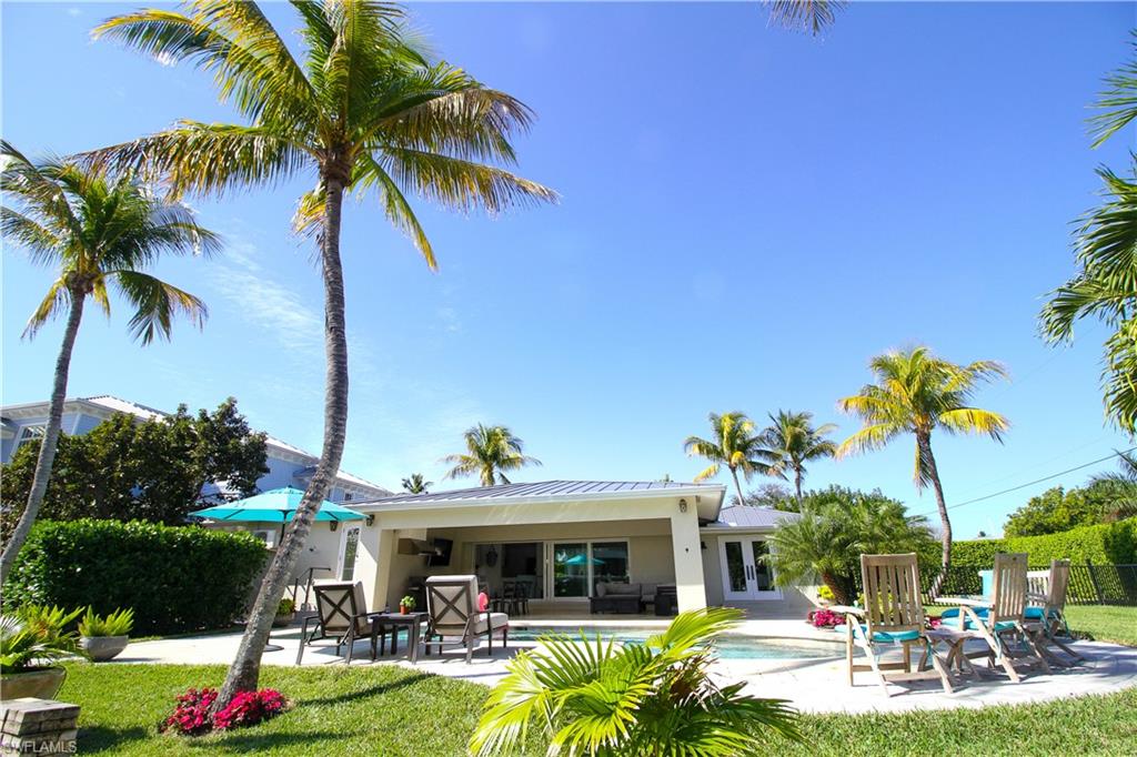 1645 Mullet Court Naples, FL 34102 - Photo 6 of 38 a view of a swimming pool with a table and chairs potted plants and palm trees