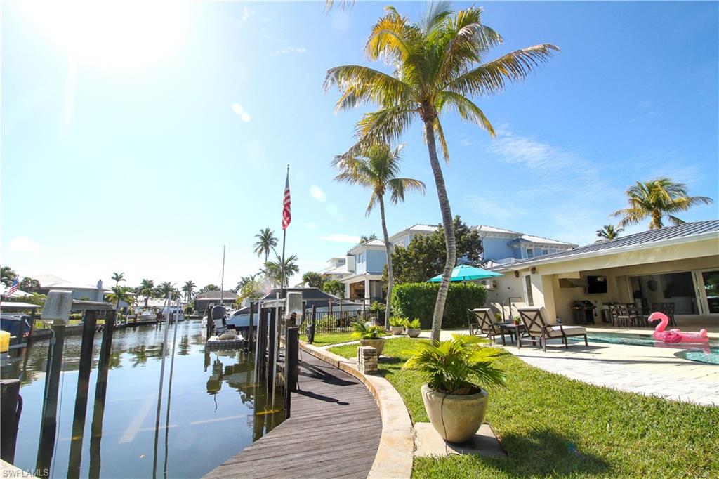 1645 Mullet Court Naples, FL 34102 - Photo 7 of 38 a view of a swimming pool with a table and chairs