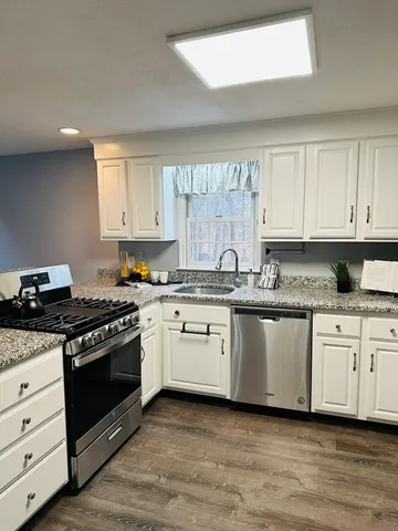 a kitchen with granite countertop white cabinets and stainless steel appliances