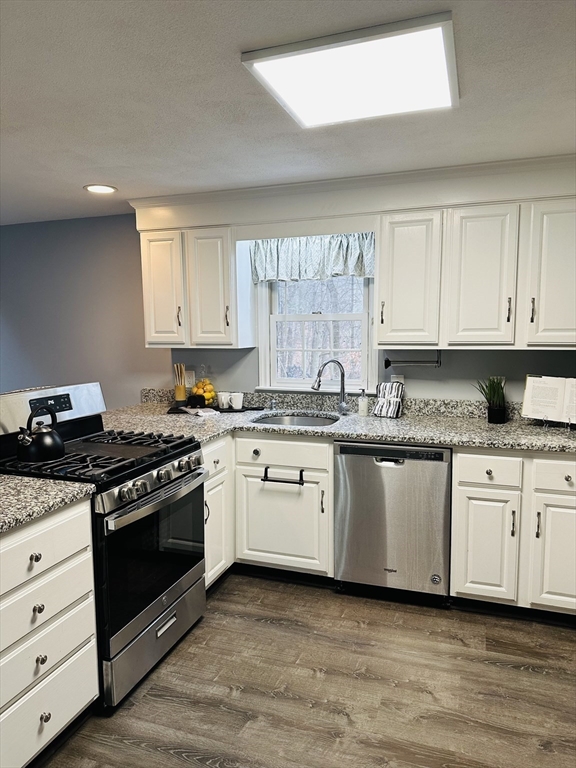 9 Averill Road, Unit B Middleton, MA 01949 - Photo 3 of 18 a kitchen with granite countertop white cabinets and stainless steel appliances