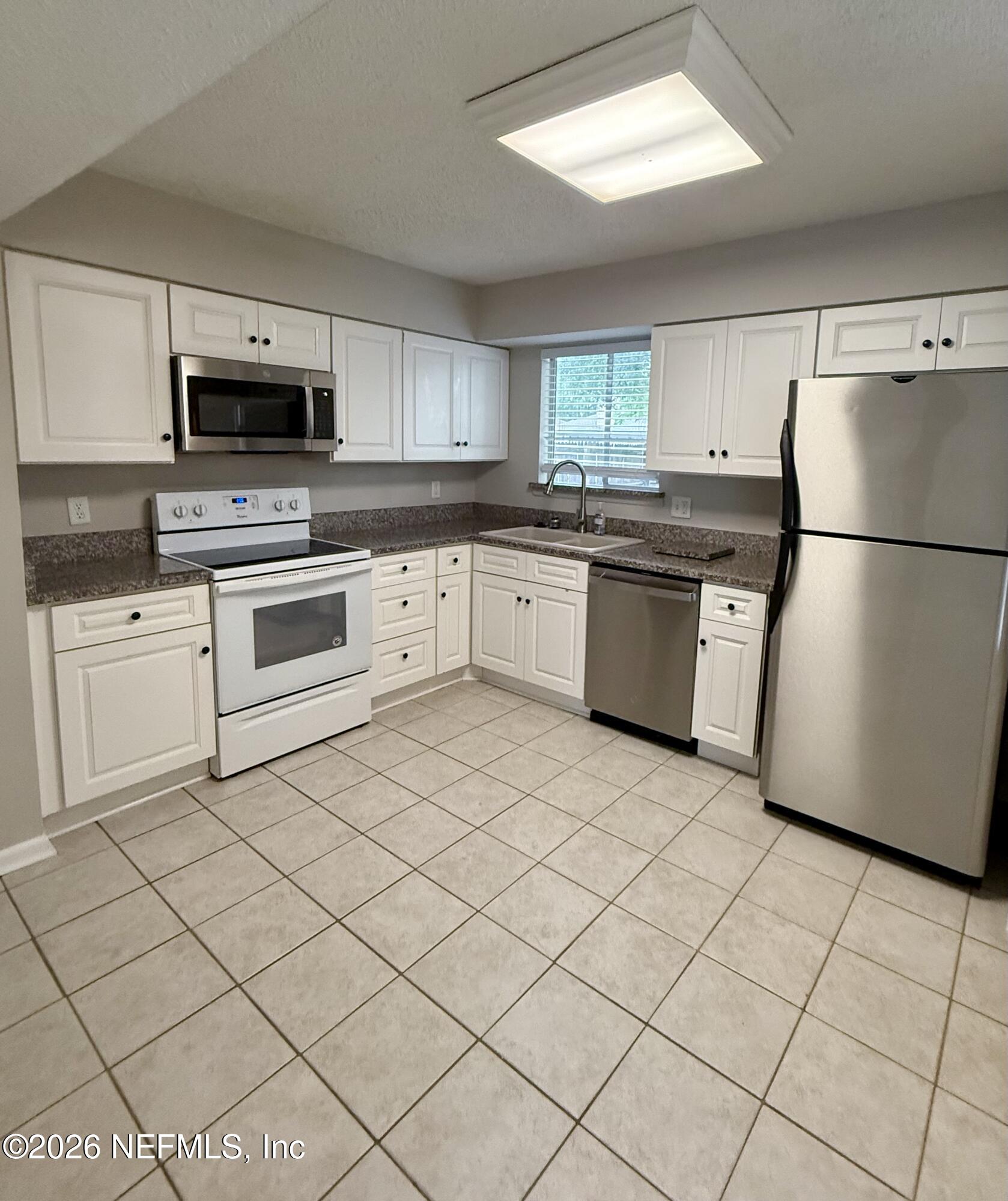 11598 West Ride Drive Jacksonville, FL 32223 - Photo 5 of 15 a kitchen with a sink a microwave and refrigerator