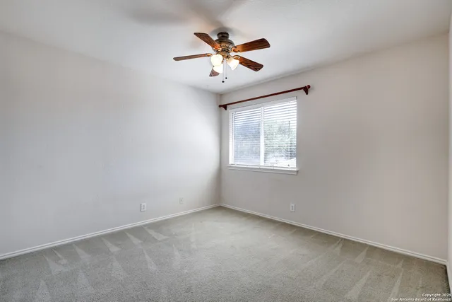an empty room with ceiling fan and window