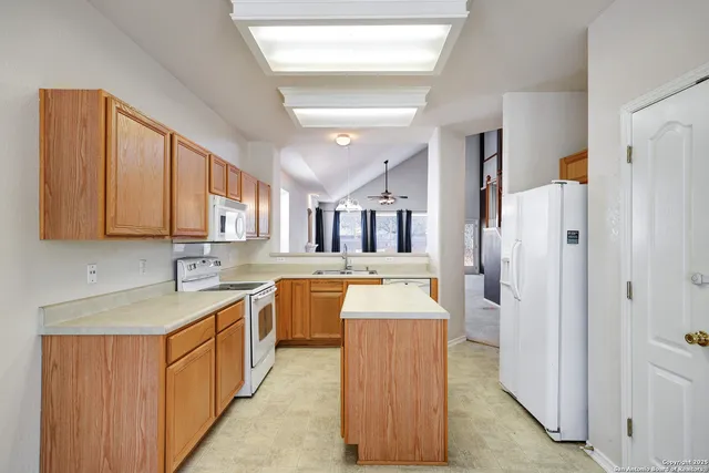 a large kitchen with stainless steel appliances granite countertop a refrigerator a sink dishwasher and white cabinets with wooden floor