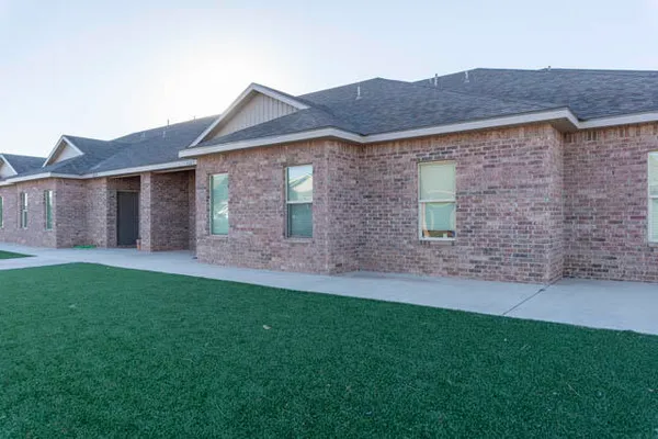 a view of a house with brick walls and a yard