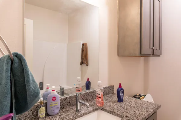 a bathroom with a granite countertop sink and a toilet