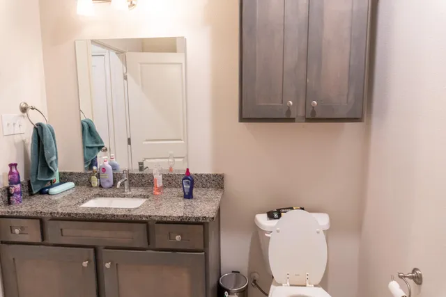 a bathroom with a granite countertop sink toilet and mirror