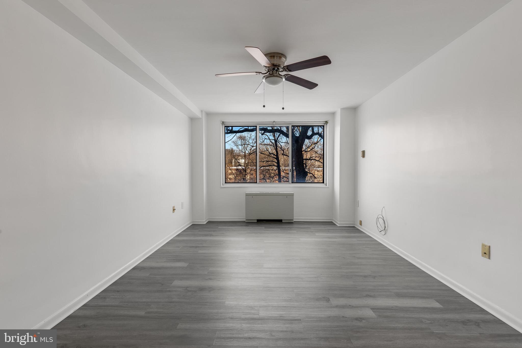10201 Grosvenor Place, Unit 204 Rockville, MD 20852 - Photo 14 of 25 an empty room with wooden floor a ceiling fan and windows