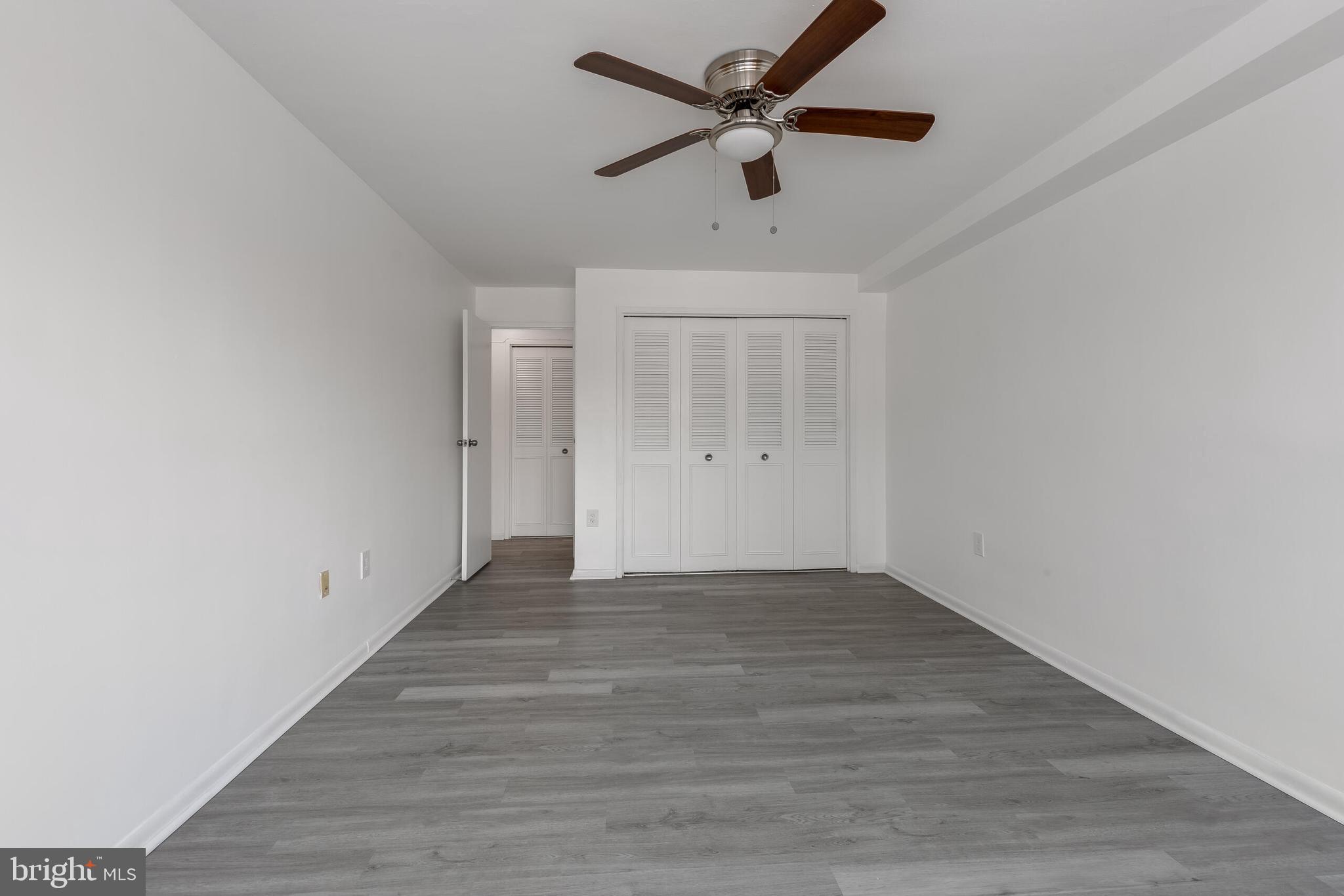 10201 Grosvenor Place, Unit 204 Rockville, MD 20852 - Photo 15 of 25 an empty room with wooden floor ceiling fan and windows