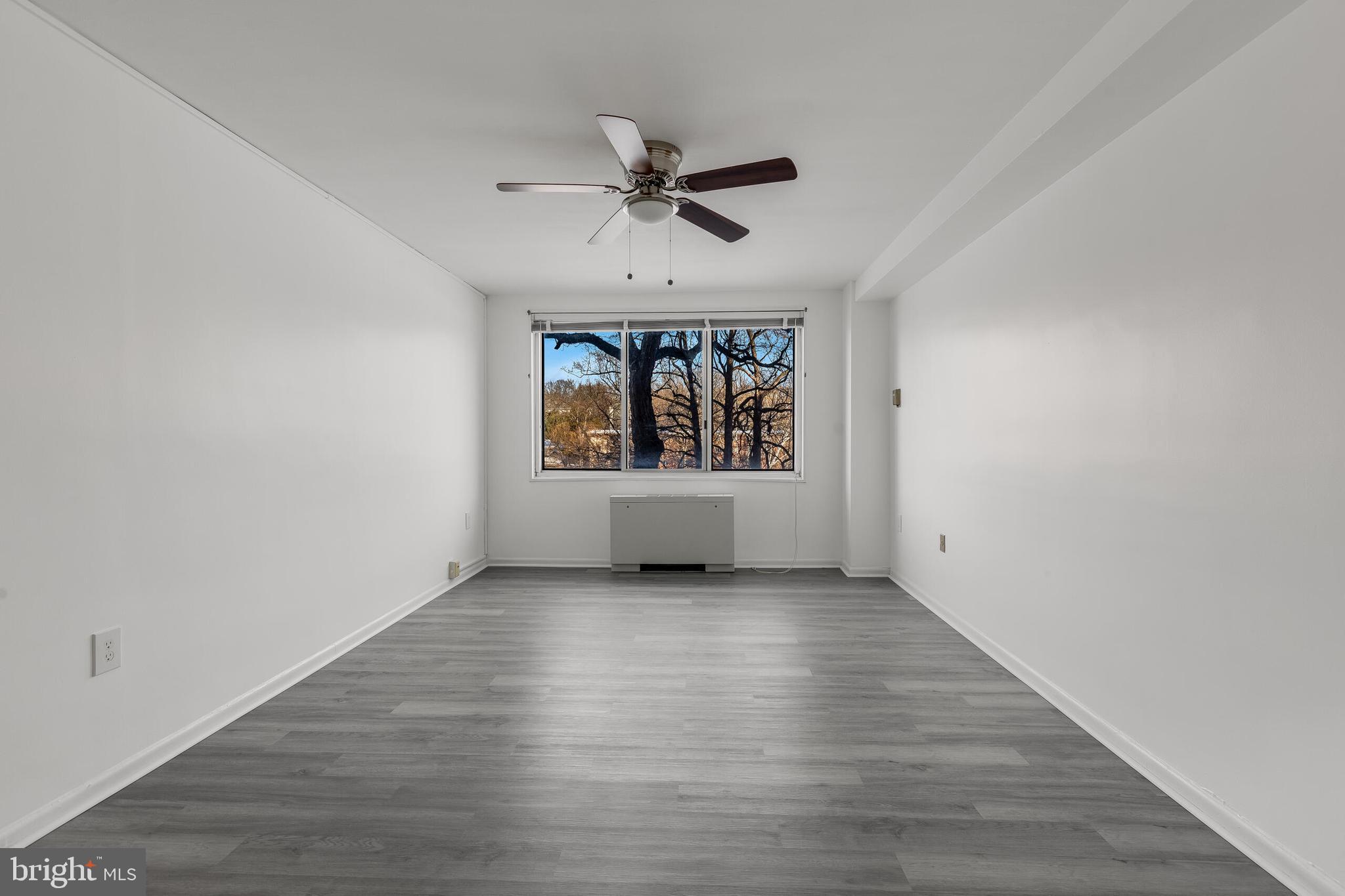 10201 Grosvenor Place, Unit 204 Rockville, MD 20852 - Photo 16 of 25 an empty room with wooden floor a ceiling fan and windows