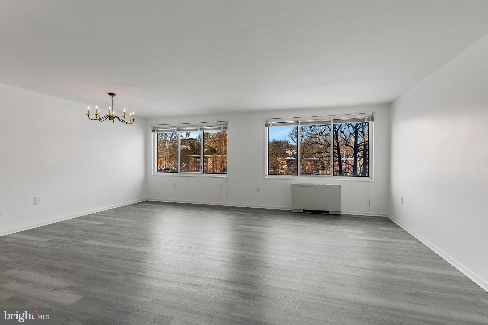 10201 Grosvenor Place, Unit 204 Rockville, MD 20852 - Photo 6 of 25 an empty room with wooden floor and windows