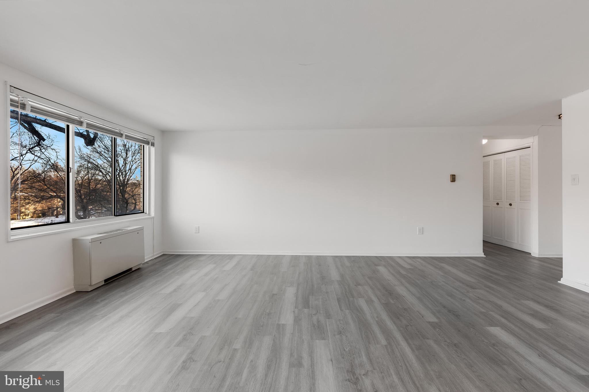 10201 Grosvenor Place, Unit 204 Rockville, MD 20852 - Photo 7 of 25 an empty room with wooden floor and windows