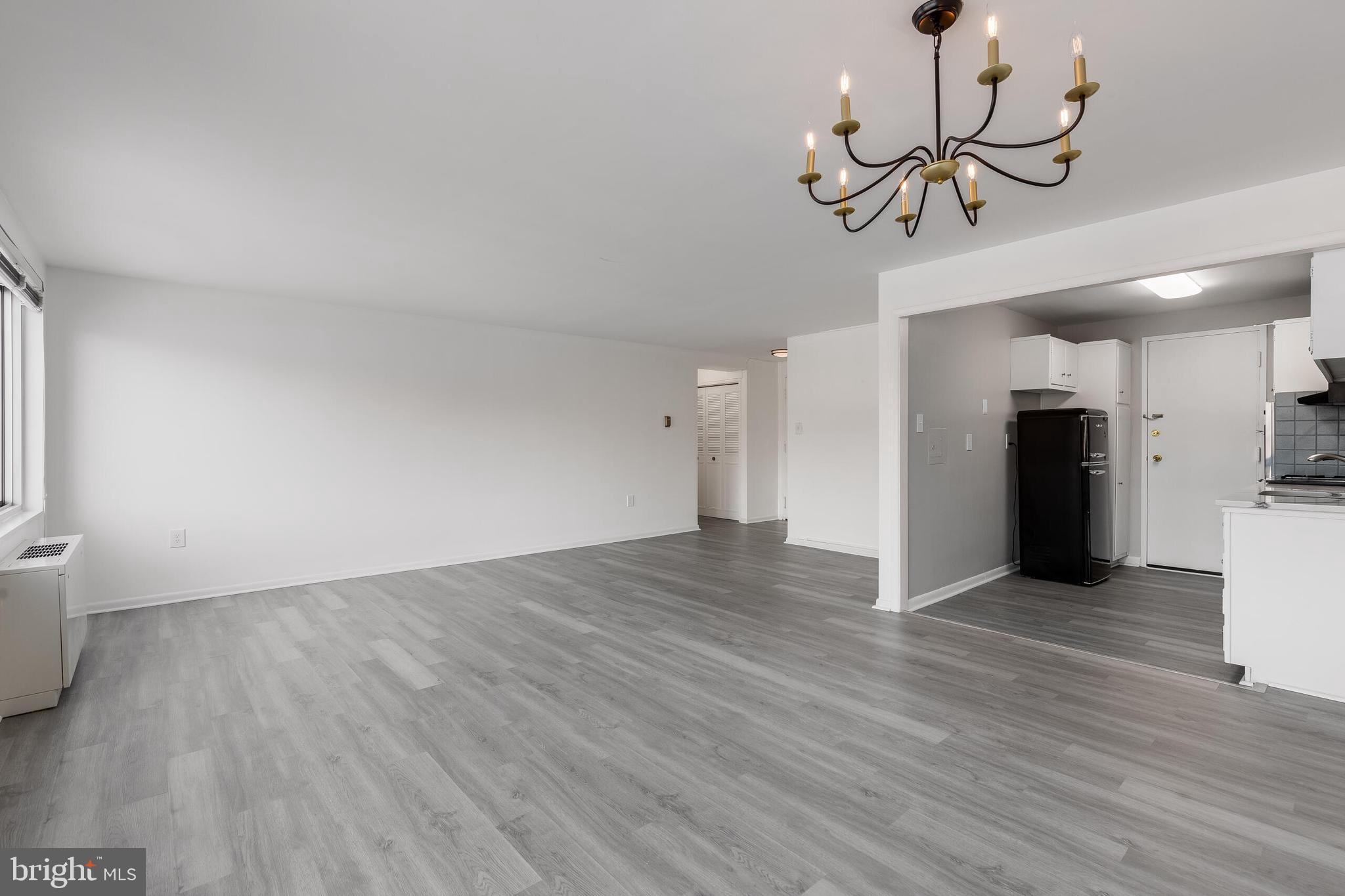10201 Grosvenor Place, Unit 204 Rockville, MD 20852 - Photo 9 of 25 a view of an empty room with wooden floor and a chandelier