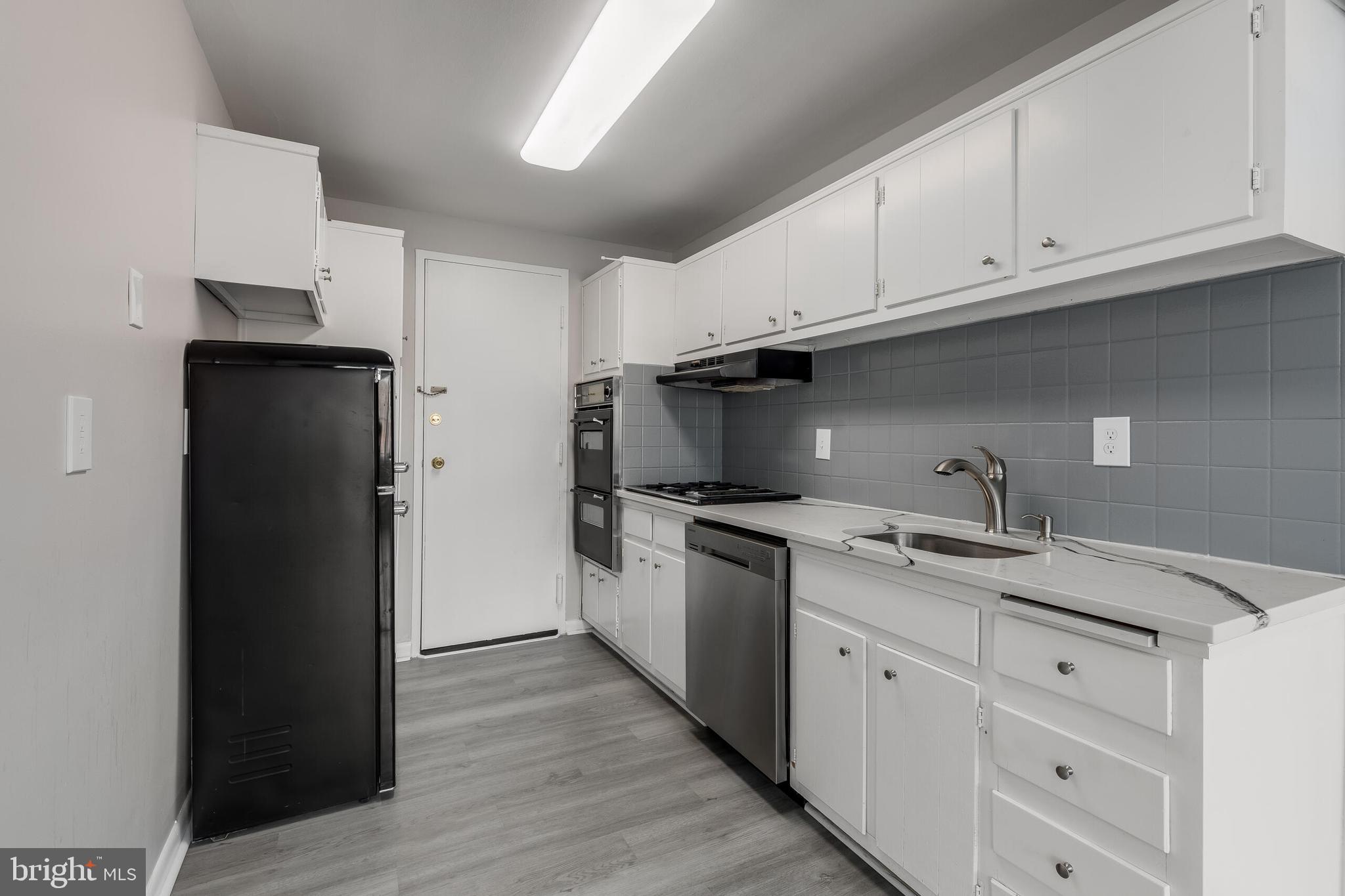 10201 Grosvenor Place, Unit 204 Rockville, MD 20852 - Photo 10 of 25 a kitchen with a sink dishwasher a refrigerator and cabinets