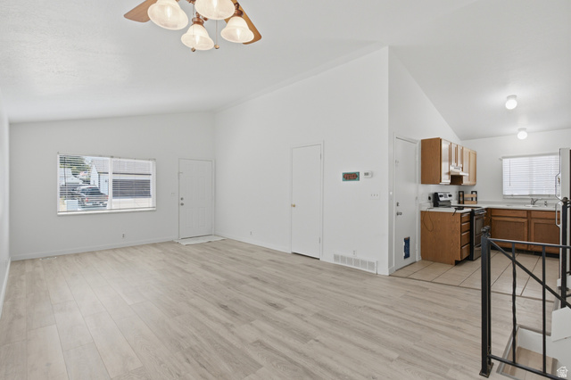 7910 Woolley Way Magna, UT 84044 - Photo 2 of 26 Spacious living area featuring light wood-finish flooring, vaulted ceilings, and a ceiling fan