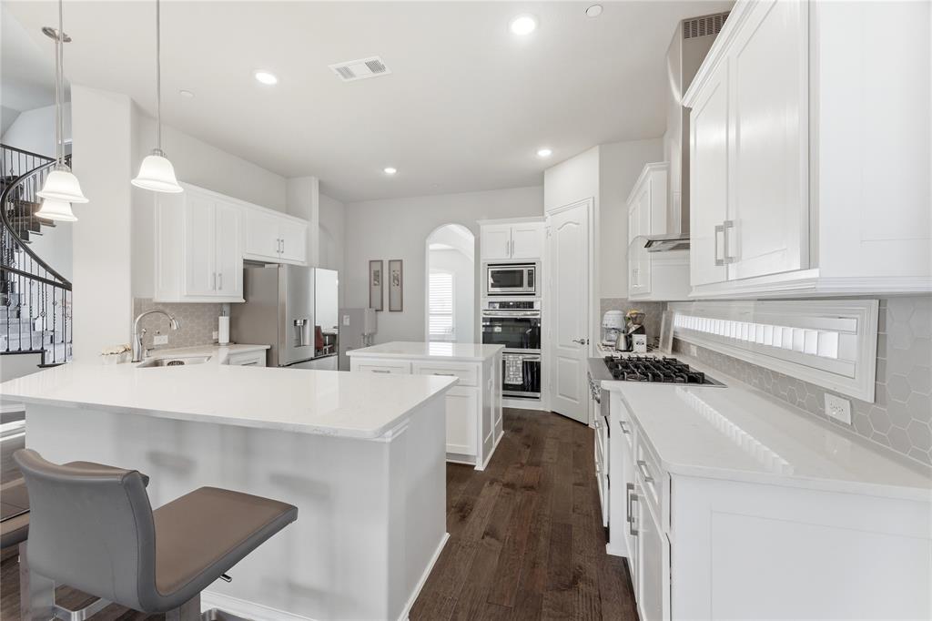 7705 Falcon Ridge Road Denton, TX 76208 - Photo 15 of 40 Kitchen with a center island, backsplash, white cabinetry, and a peninsula