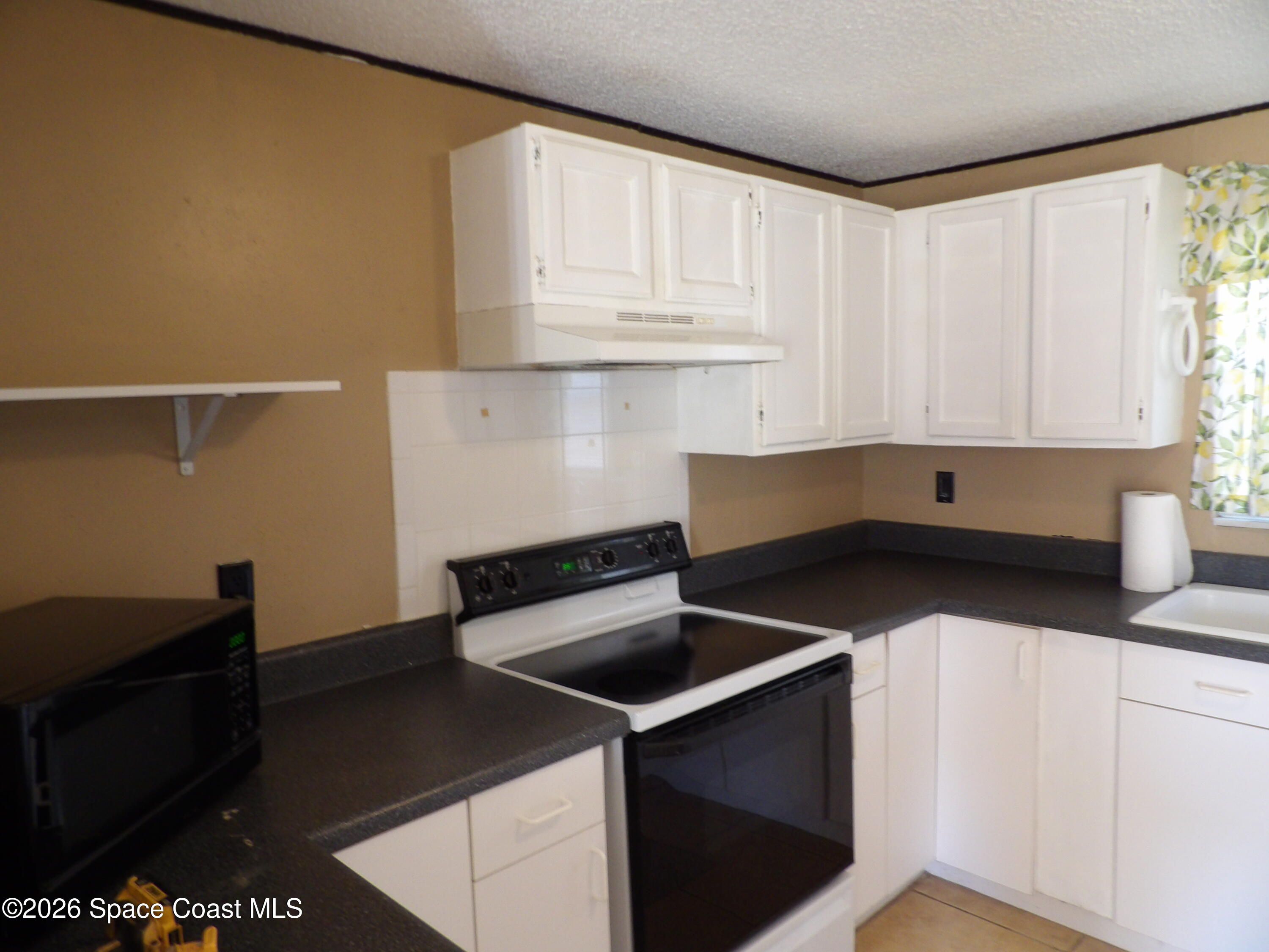 6318 Hudson Road Cocoa, FL 32927 - Photo 8 of 38 a kitchen with granite countertop white cabinets and black appliances