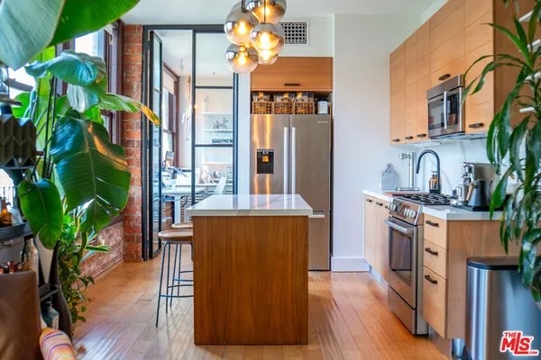 a kitchen with stainless steel appliances granite countertop a stove a sink dishwasher and a refrigerator with wooden floor