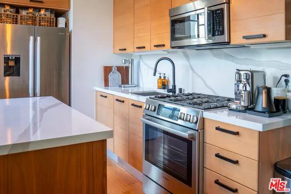 a kitchen with stainless steel appliances granite countertop a refrigerator a stove and a sink with wooden floor