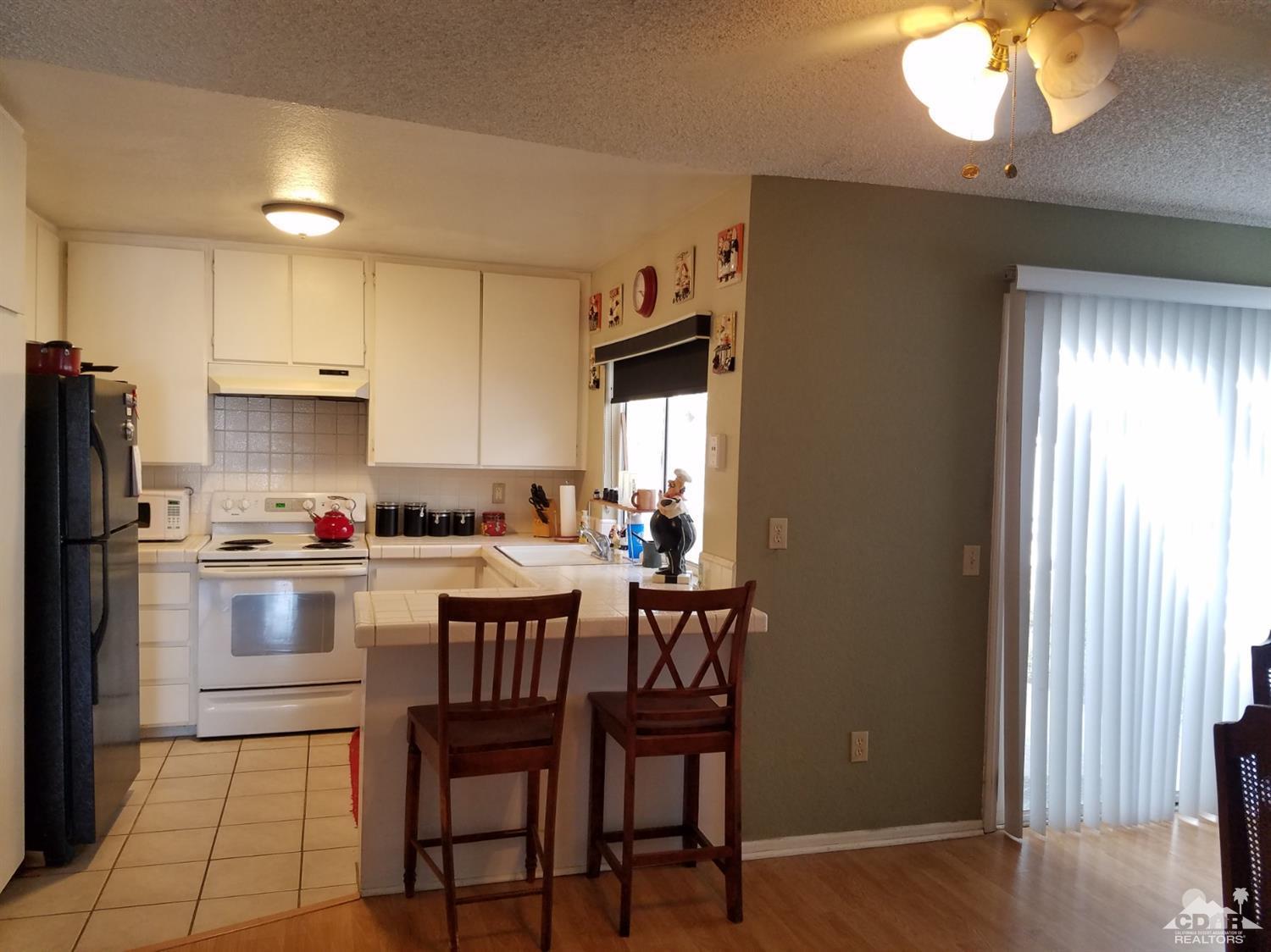 3166 Tomahawk Circle Riverside, CA 92503 - Photo 3 of 29 a kitchen with a dining table chairs refrigerator and cabinets