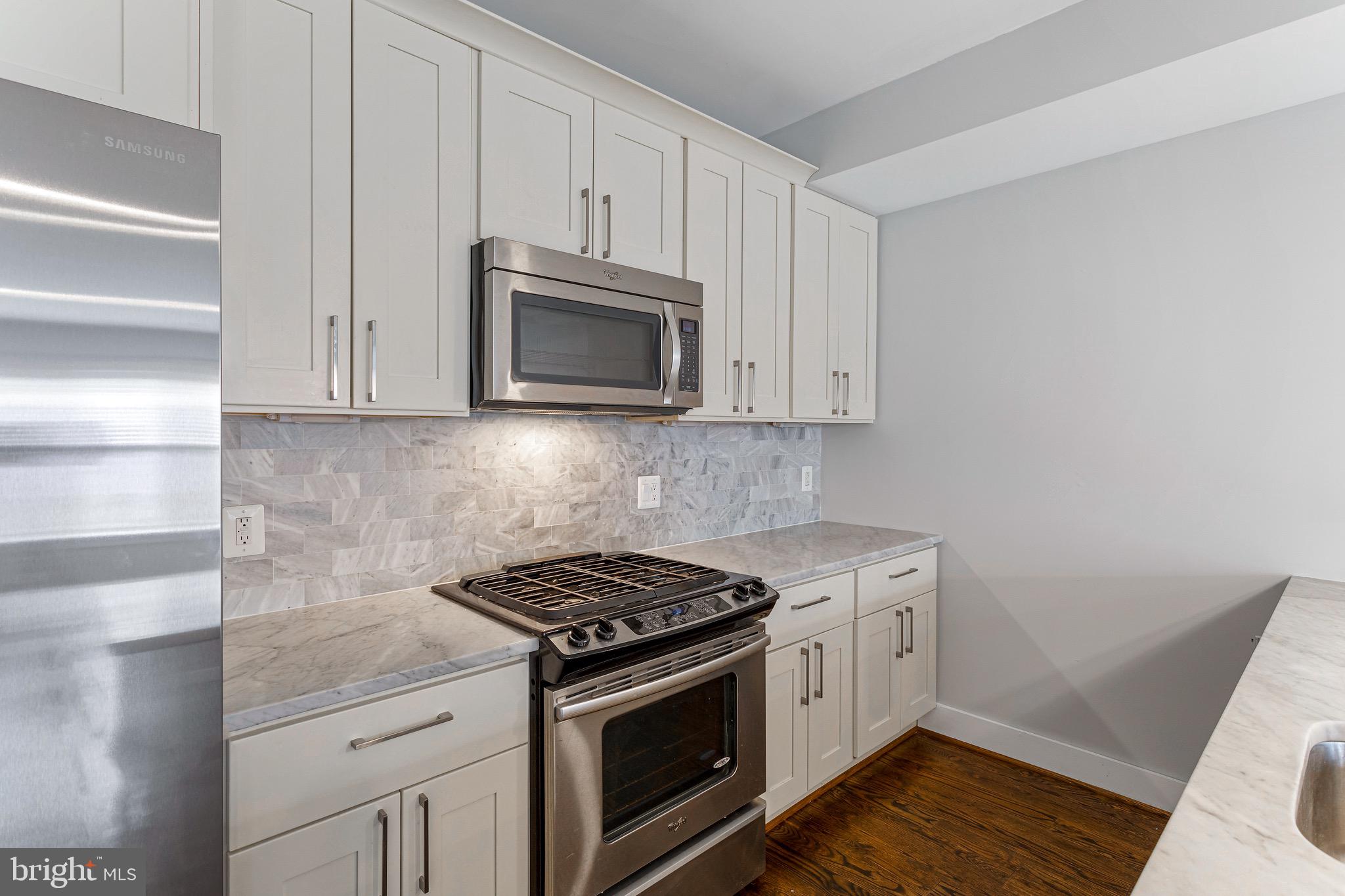 1221 Kenyon Street Northwest, Unit 2 Washington, DC 20010 - Photo 4 of 26 a kitchen with granite countertop white cabinets and stainless steel appliances