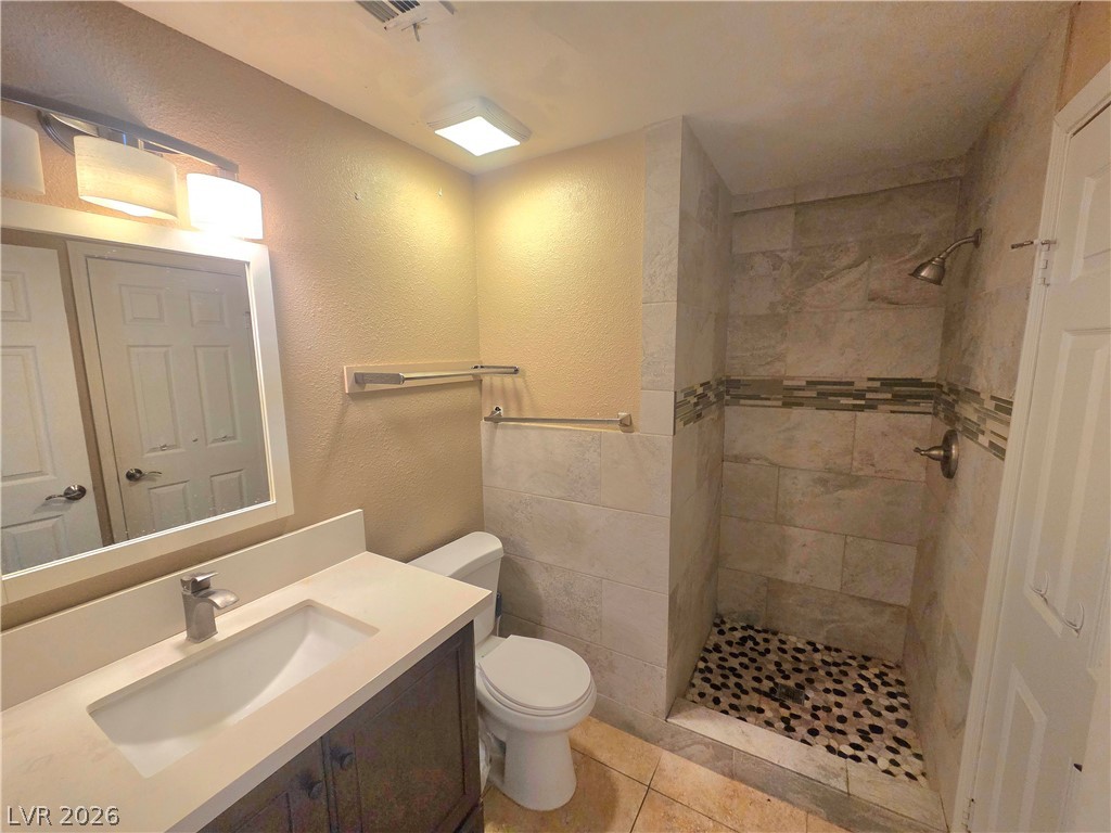 3648 Bronco Road Las Vegas, NV 89103 - Photo 8 of 24 A refined bathroom features a stylish vanity, contemporary lighting, and a walk-in shower with natural stone tiling.