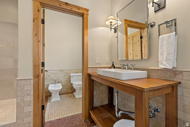 105 River Bend Circle, Unit 105 Springdale, UT 84767 - Photo 15 of 56 Bathroom featuring a wood-finish vanity with a rectangular vessel sink, wall-mounted mirror, and tile wainscoting