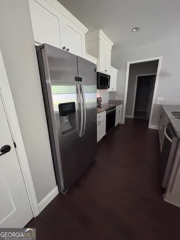 a kitchen with stainless steel appliances a refrigerator a sink a stove and white cabinets