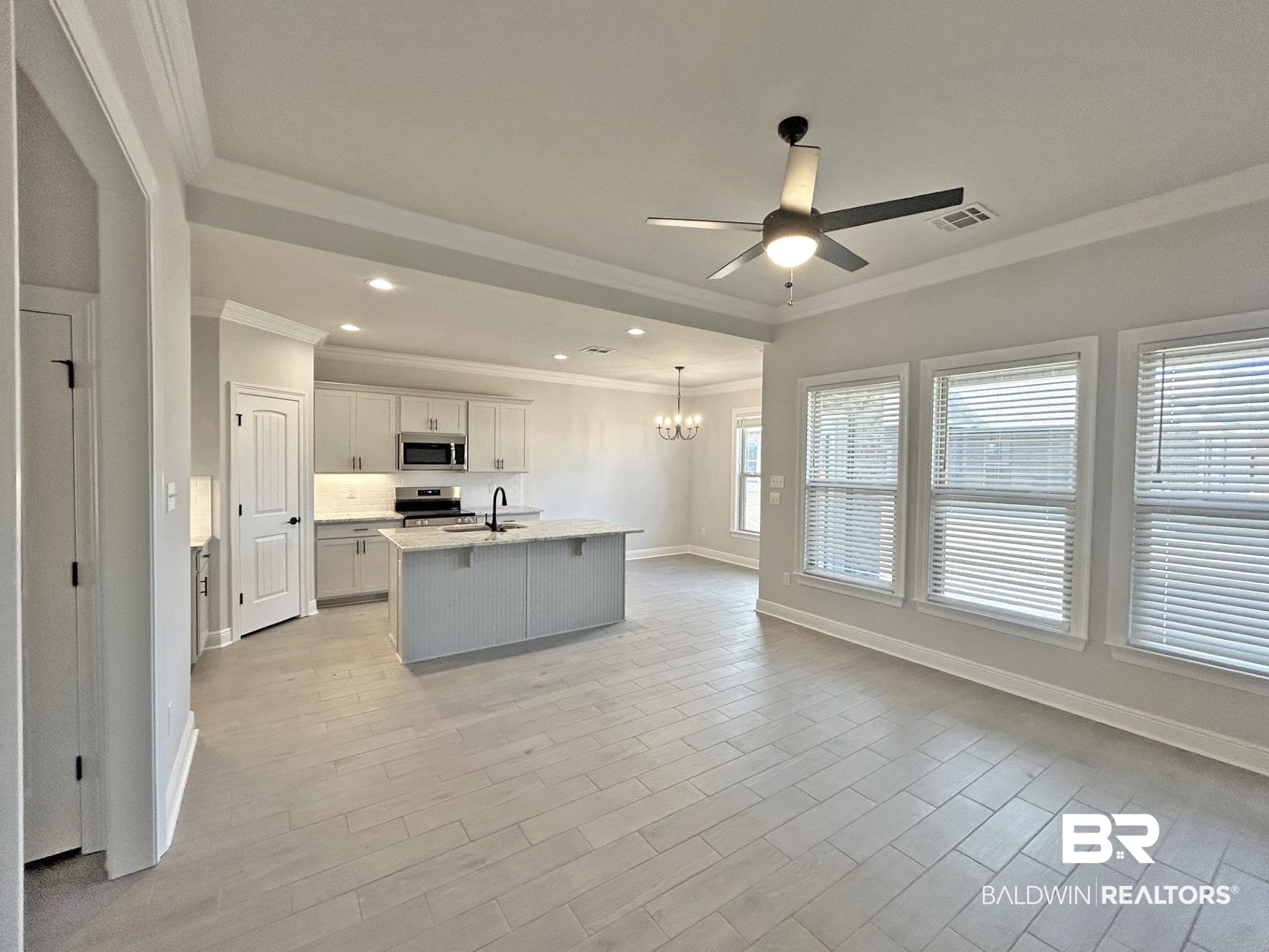 1748 Breckinridge Place Foley, AL 36535 - Photo 7 of 25 Kitchen featuring ceiling fan, a kitchen island with sink, a chandelier, stainless steel appliances, and wood tiled floors