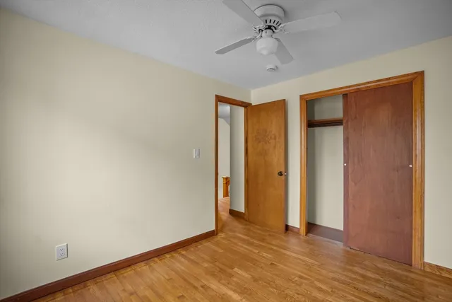 an empty room with wooden floor and ceiling fan