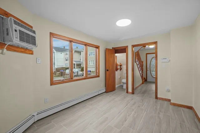 a view of an empty room with a window and wooden floor