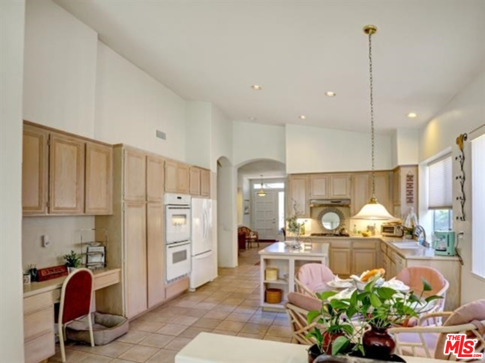 11063 Mulgrave Road San Diego, CA 92131 - Photo 15 of 30 a kitchen with stainless steel appliances kitchen island granite countertop a refrigerator oven a sink a dining table and chairs with wooden floor
