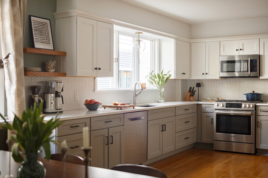 107 Grozier Road, Unit 1 Cambridge, MA 02138 - Photo 8 of 23 a kitchen with stainless steel appliances a stove a sink cabinets and a window