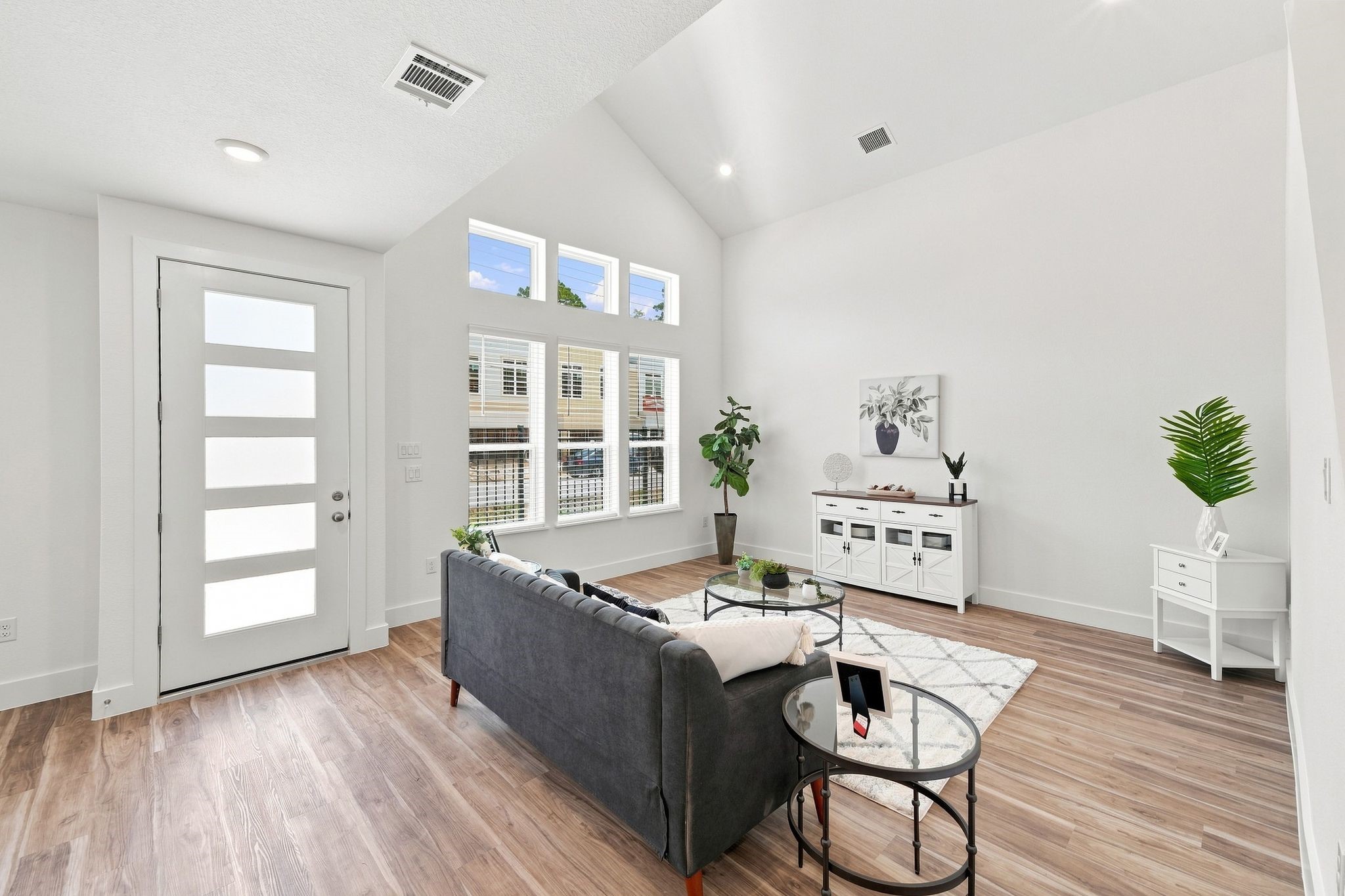 6063 Cebra Street Houston, TX 77091 - Photo 23 of 50 Spacious living room with soaring ceilings, abundant natural light, and a modern front door complemented by multiple windows. Photos are from a different property with the same floor plan, features, and finishes. **Orientation may vary.**