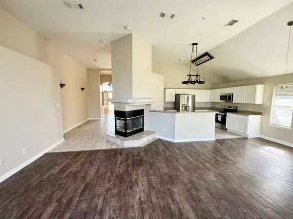 an empty room with wooden floor fireplace and windows