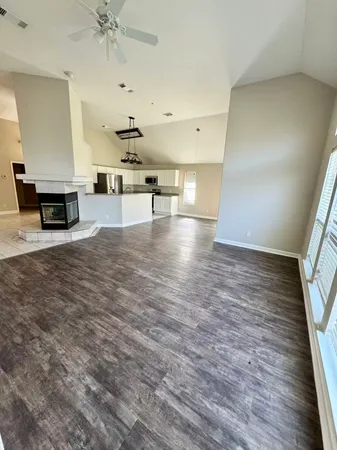 an empty room with wooden floor ceiling fan and windows