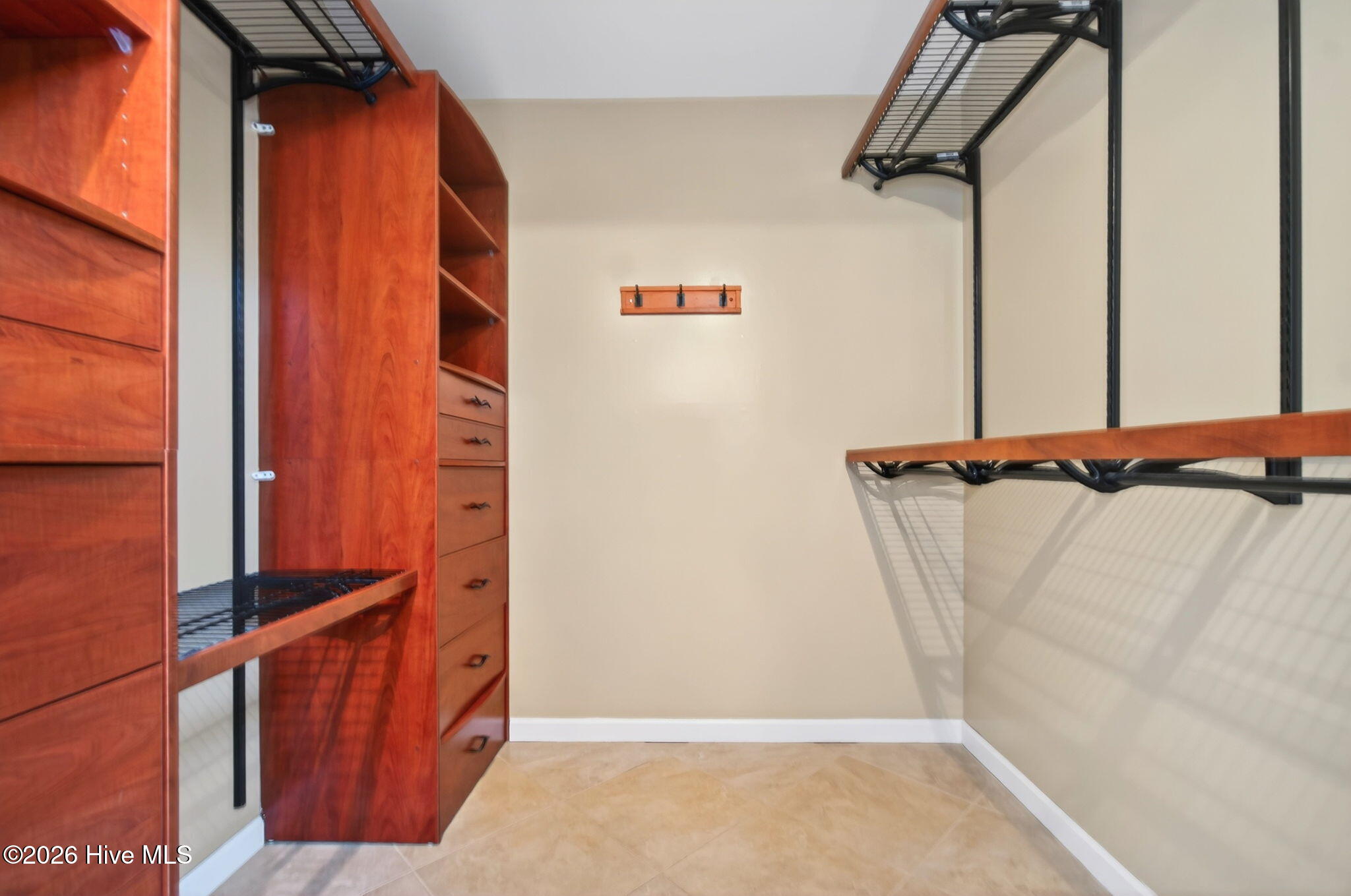 7609 Hawk Road Wilmington, NC 28411 - Photo 23 of 45 7x7 primary walk-in closet with custom built-ins and tile floor