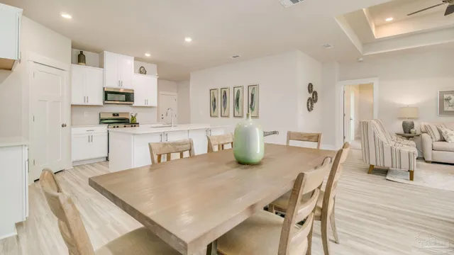 a kitchen with stainless steel appliances granite countertop a dining table chairs and refrigerator