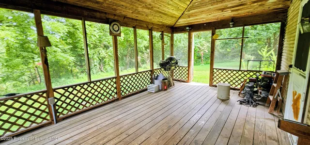 a balcony with wooden floor outdoor seating and yard in the back