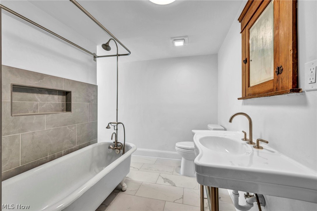 2135 Coventry Road, Unit UP Cleveland Heights, OH 44118 - Photo 31 of 38 Clawfoot soaking tub with integrated shower, tiled shower surround, recessed shower niche, white porcelain pedestal sink with bronze-finish fixtures, and a wood-frame medicine cabinet